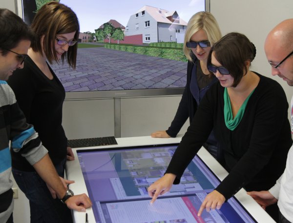 Studierende betrachten an einem Touch Table ein 3D-Stadtmodell Studierende betrachten an einem Touch Table ein 3D-Stadtmodell