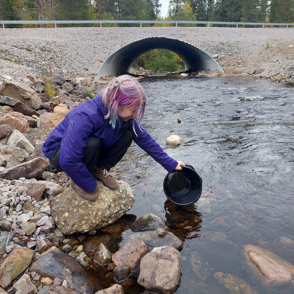 Nathalie nimmt eine Wasserprobe an einem Fluss