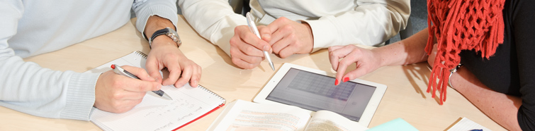 Vogelperspektive auf einen Gruppenarbeitstisch mit Studierenden, sichtbar sind nur die Hände, Stifte, Papier und ein Tablet Vogelperspektive auf einen Gruppenarbeitstisch mit Studierenden, sichtbar sind nur die Hände, Stifte, Papier und ein Tablet